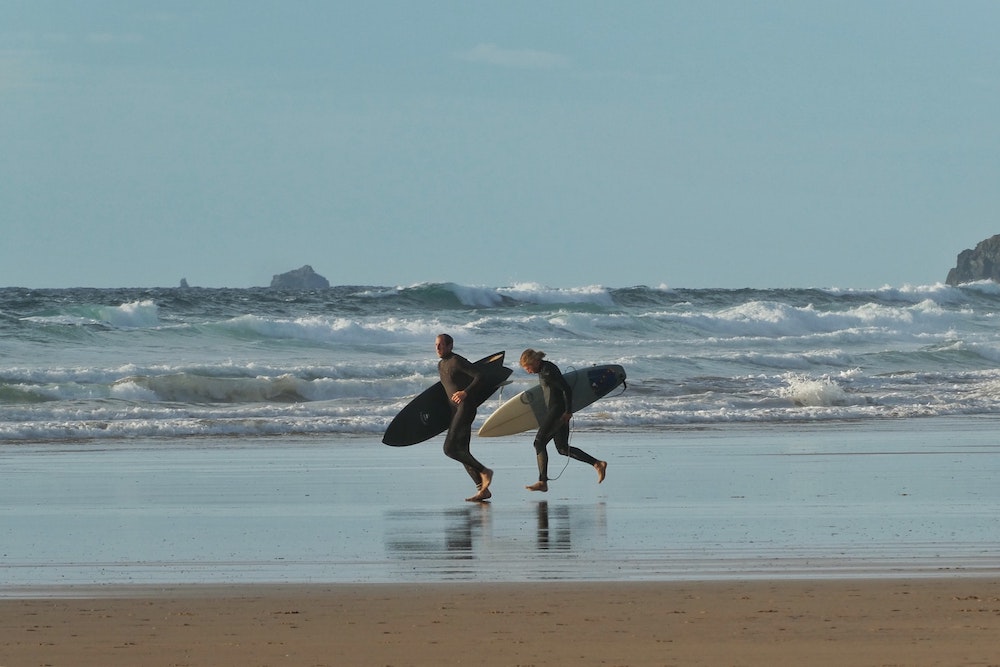 Surfers on beach at Watergate Bay